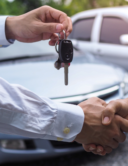 car key handover and handshake at dealership