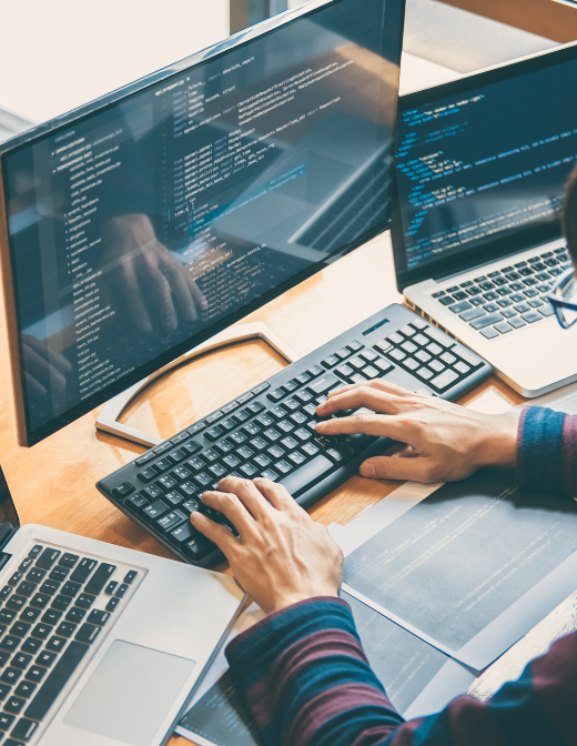 programmer coding on multiple computer screens